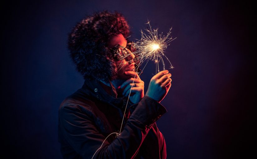 Man in glasses and hat looks at sparkler
